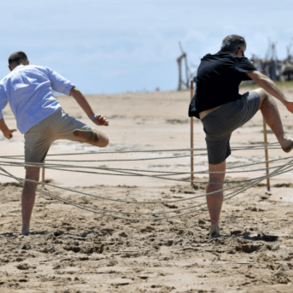 Deux hommes participant à une épreuve d'agilité sur une plage lors d'une activité de teambuilding.