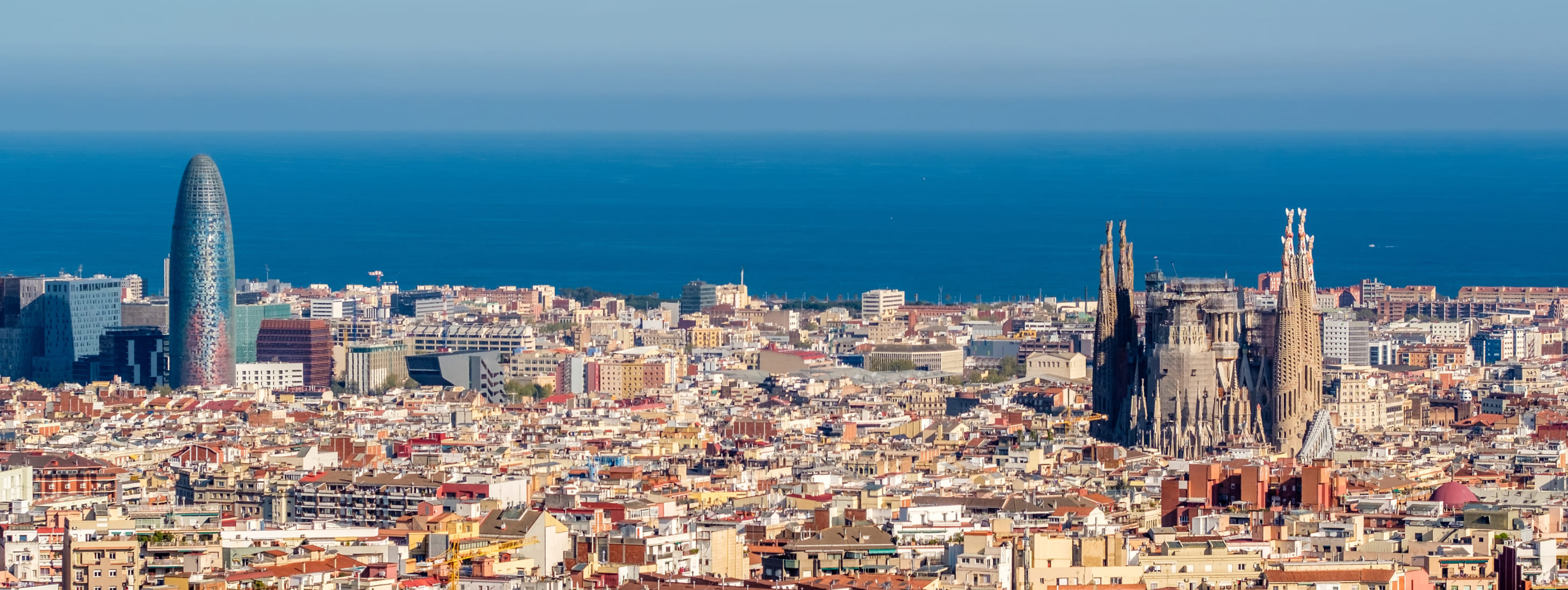 Vue aérienne de Barcelone mettant en évidence la Sagrada Família et la tour Glòries sur fond de mer Méditerranée.