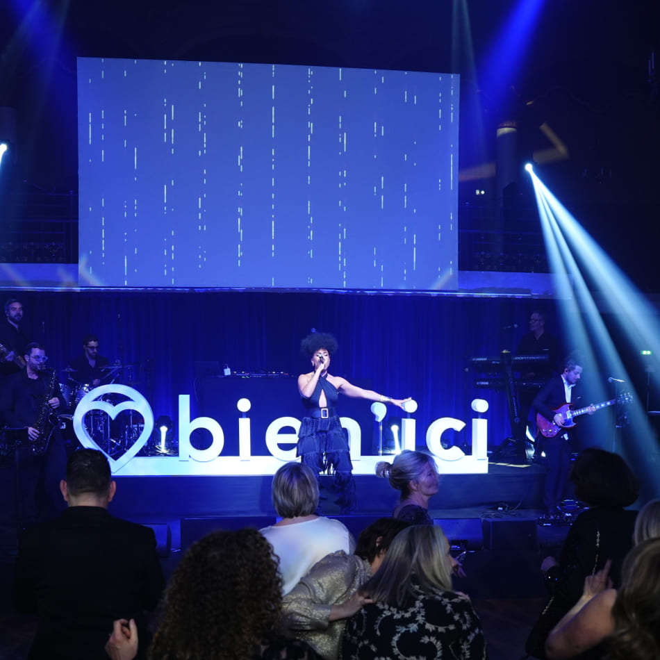 Une chanteuse se produit sur scène devant un logo "bien'ici" lumineux lors d'un événement festif.