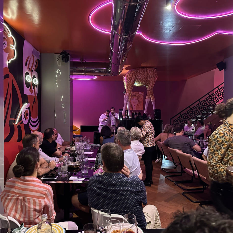 Dîner animé dans un restaurant au décor original avec éclairage néon rose et une statue de girafe.
