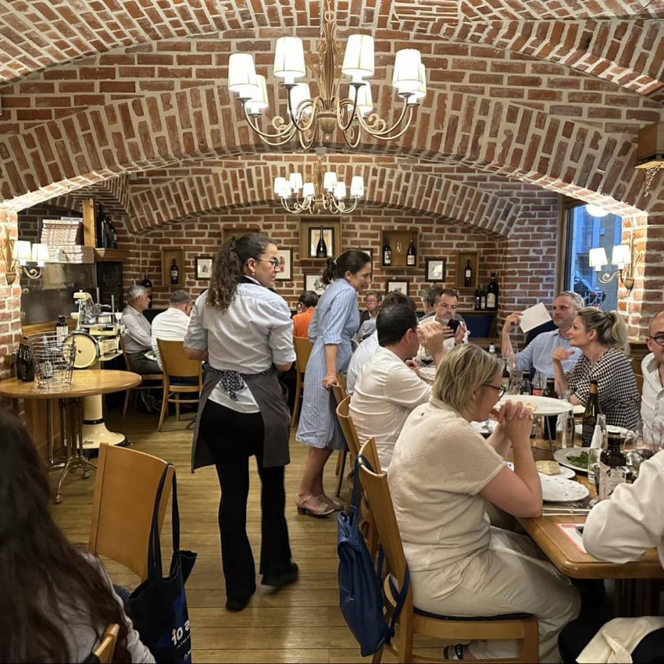 Clients attablés dans un restaurant chaleureux sous des voûtes en briques avec service en salle.