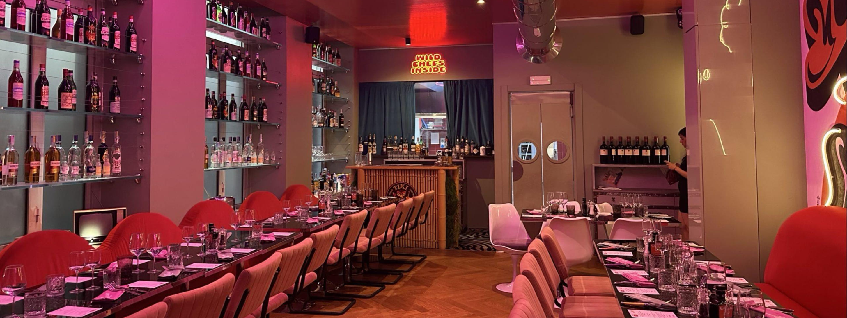 Vue d'ensemble d'une salle de restaurant moderne et colorée avec de longues tables prêtes pour un banquet.