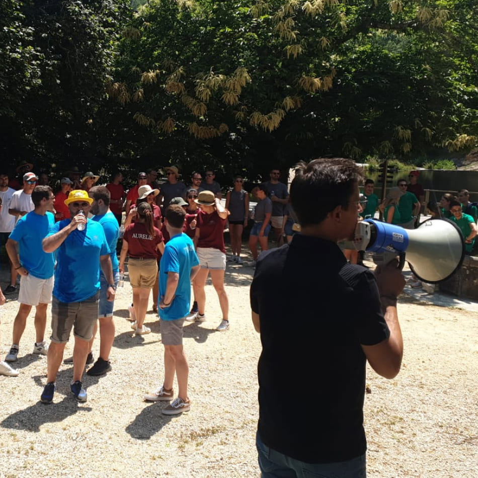Homme de dos utilisant un mégaphone pour s'adresser à un large groupe de personnes réunies en plein air.
