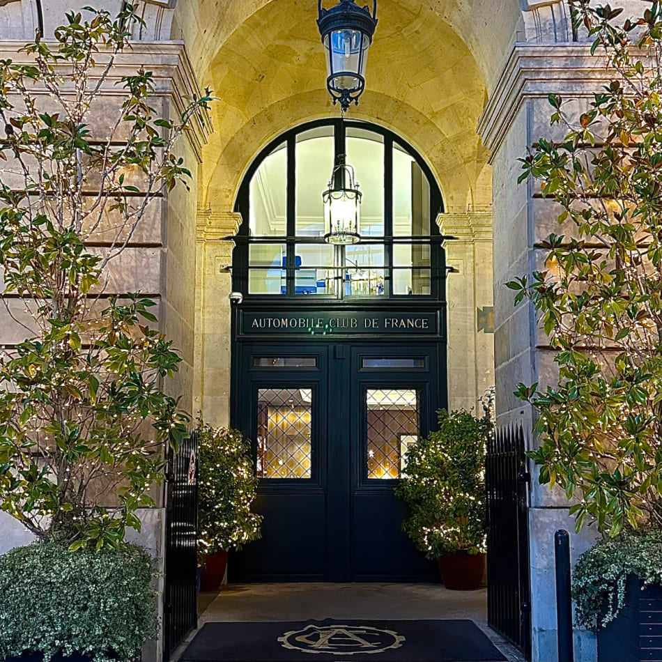 Entrée de prestige de l'Automobile Club de France à Paris, encadrée de végétation et éclairée de nuit.