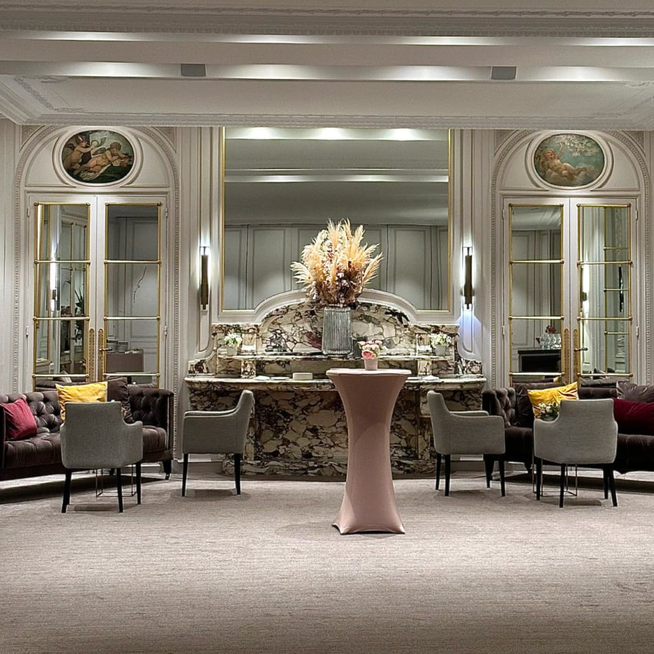 Salon de réception luxueux avec une cheminée en marbre, des fauteuils confortables et une décoration florale soignée.