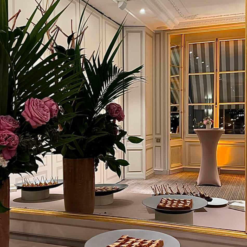 Buffet de mignardises et fleurs fraîches reflétés dans un grand miroir dans un cadre classique élégant.