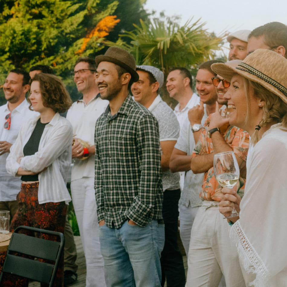Groupe de collaborateurs souriants et détendus lors d'un événement de teambuilding en extérieur.