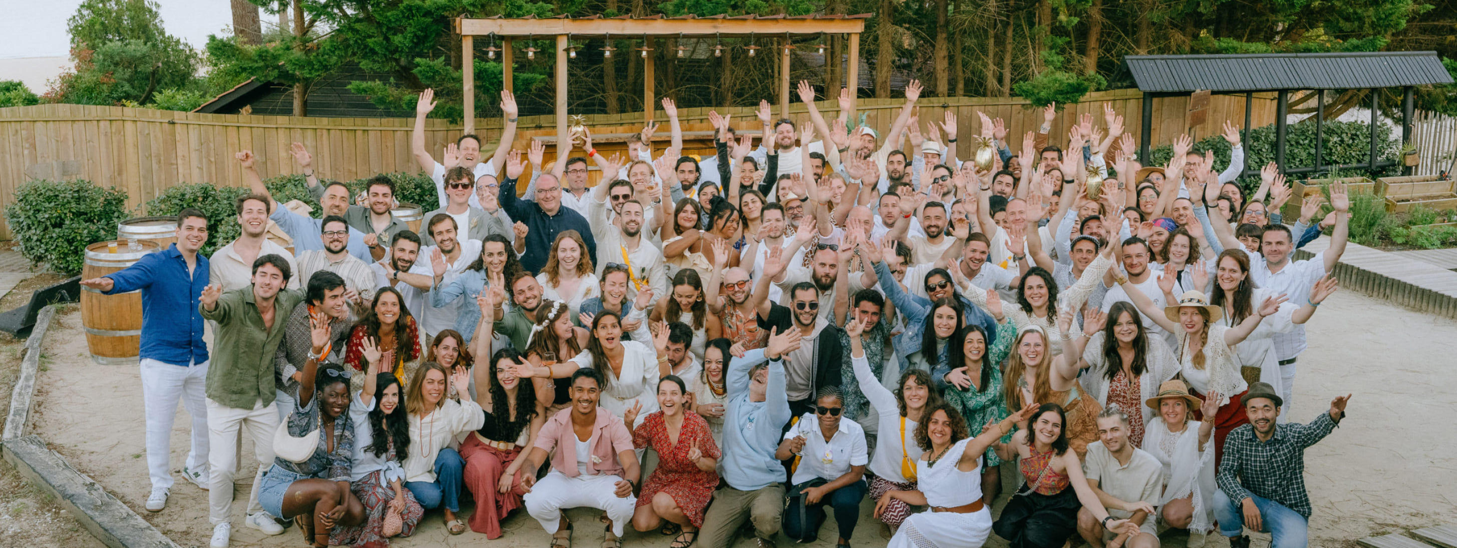 Grande photo de groupe de l'ensemble des participants joyeux levant les bras lors d'un séminaire en plein air.
