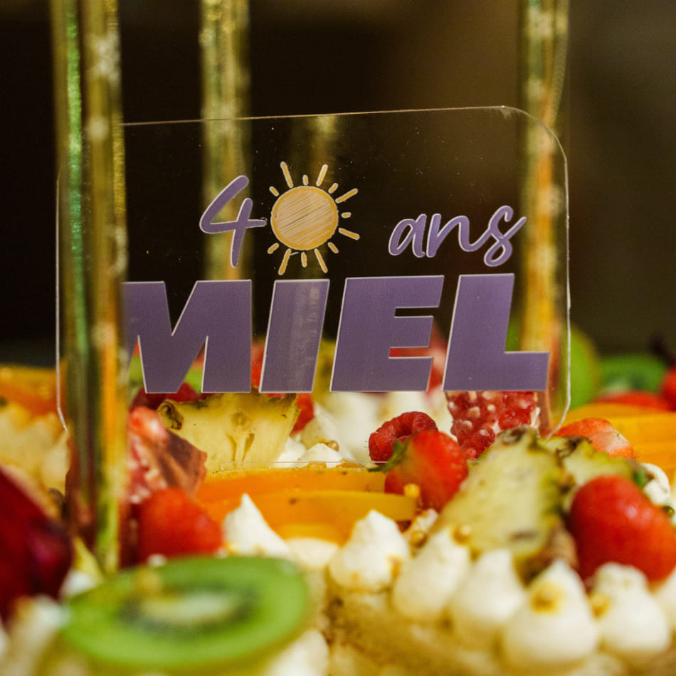 Gros plan sur une décoration de gâteau aux fruits indiquant « 40 ans MIEL ».
