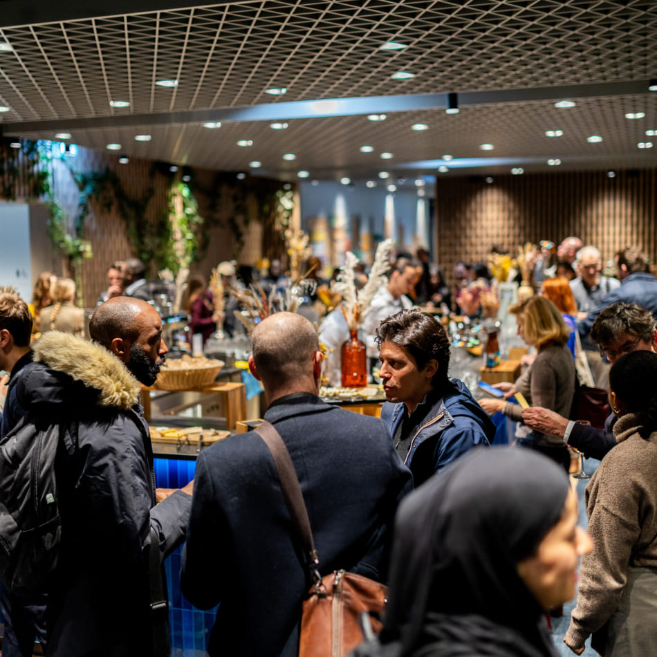 Des participants discutent de manière informelle dans un espace de networking convivial avec un bar en arrière-plan.
