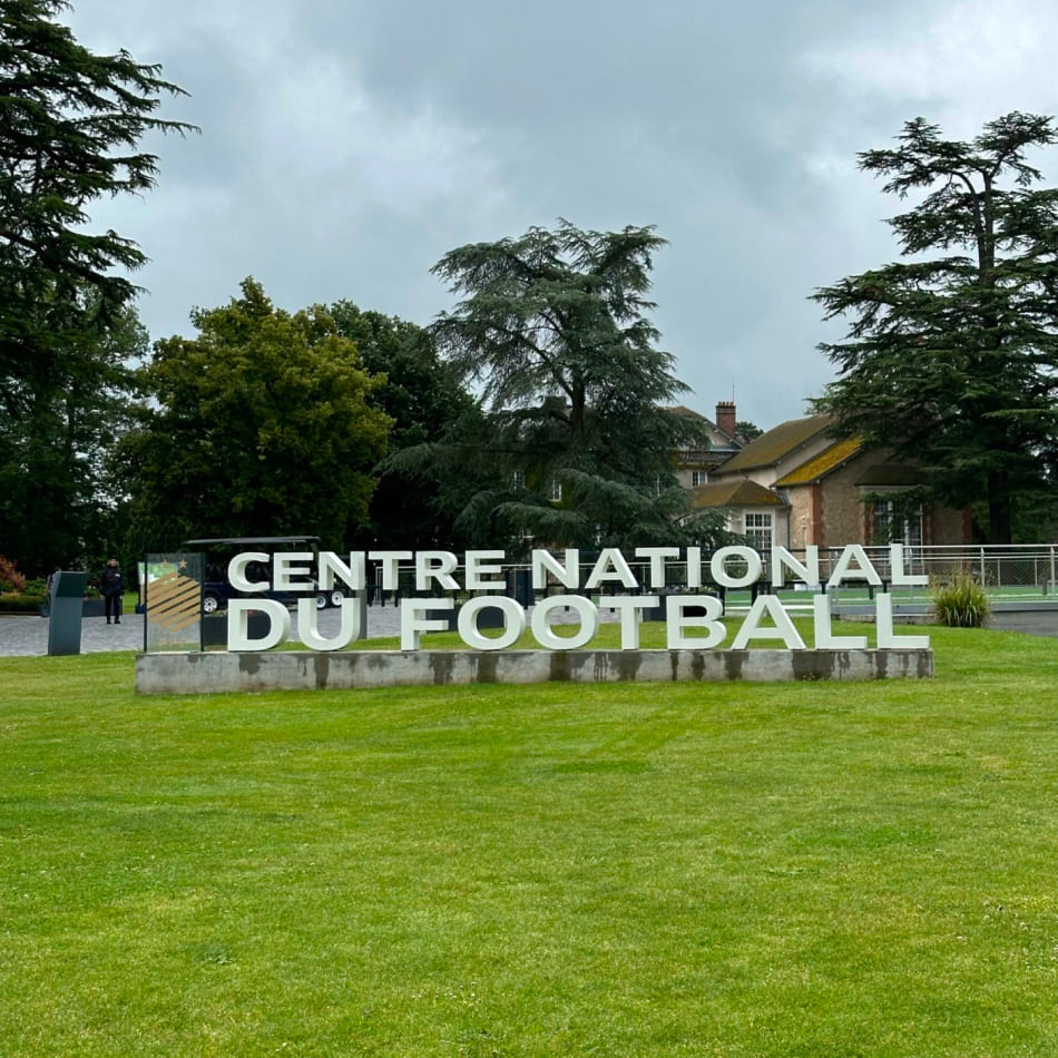Enseigne monumentale marquant l'entrée du Centre National du Football à Clairefontaine sur un domaine verdoyant.