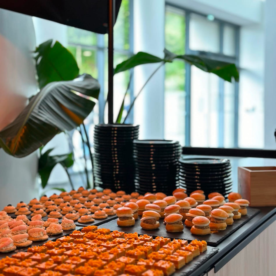 Buffet traiteur élégant présentant des assortiments de pièces cocktail salées et mini-burgers raffinés.